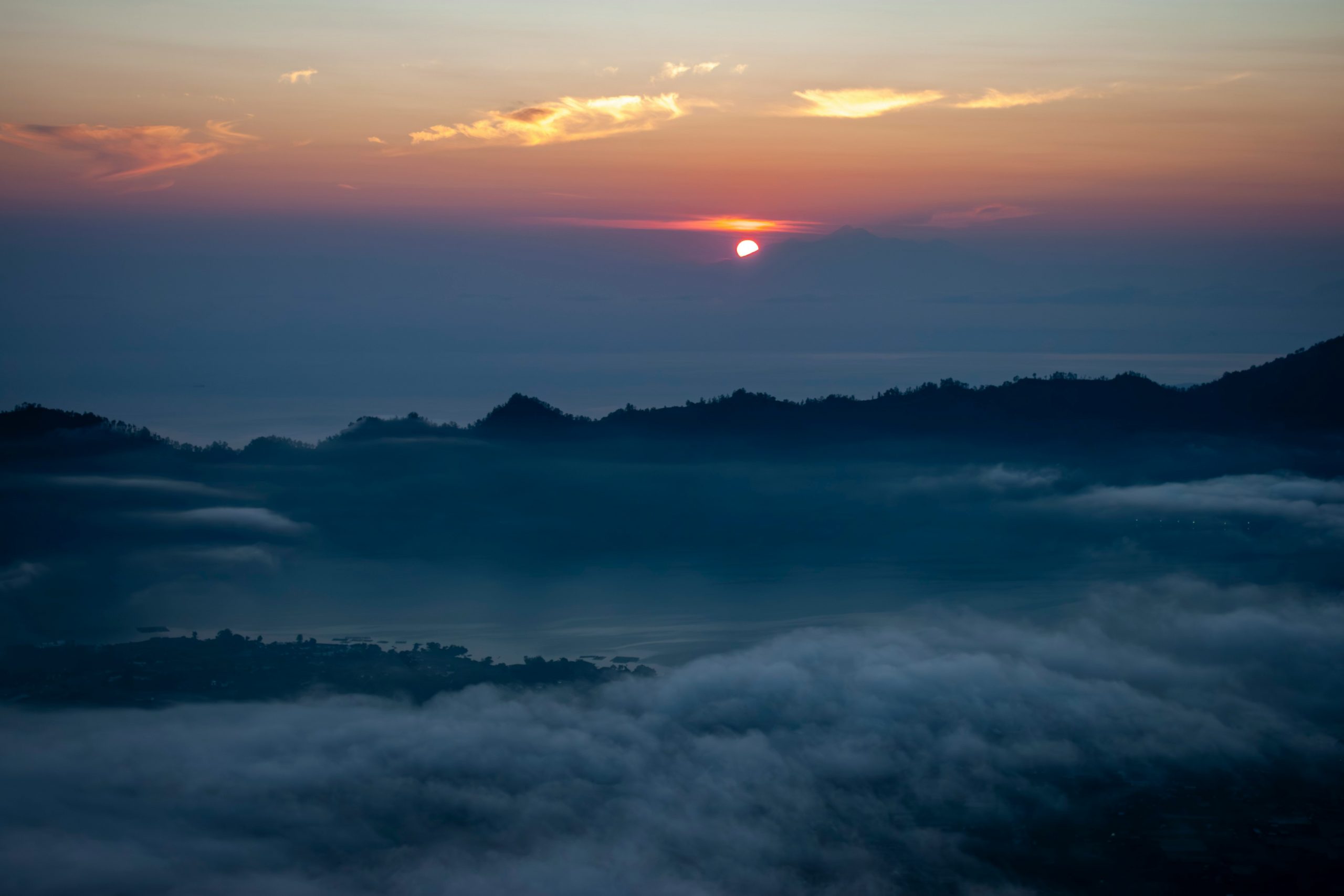 Hikers trekking Mount Batur volcano at dawn.