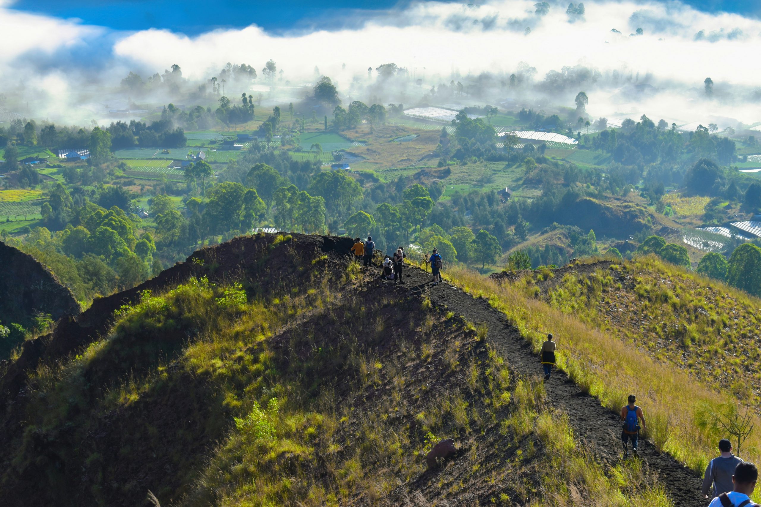 Hikers trekking Mount Batur volcano at dawn.